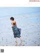 A woman walking on a beach near the ocean.