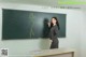 A woman standing in front of a blackboard in a classroom.