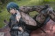 A woman with blue hair and black stockings laying on a blanket.