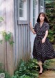 A woman standing in front of a wooden house.