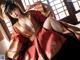 A woman in a red and gold kimono sitting on a window sill.