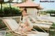 A woman in a blue bikini sitting on a lounge chair.