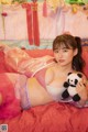 A woman laying on a bed holding a stuffed panda bear.