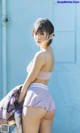 A woman in a pink bra top and purple shorts posing for a picture.