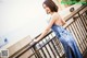 A woman in a blue dress standing on a balcony.