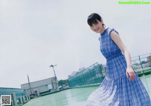 A woman in a blue and white dress standing on a roof.